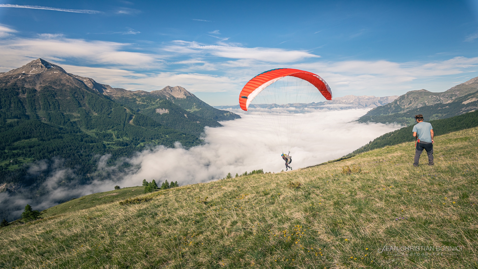Moniteur de parapente diplômé qui guide un stagiaire lors d'un stage initiation en parapente au dessus d'une mer de nuage